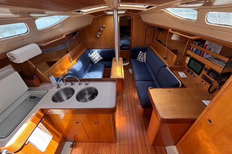 Slide: The Image of Interior of a 1990 Beneteau Oceanis 350 sailboat with wood finish and blue seating. - 4
