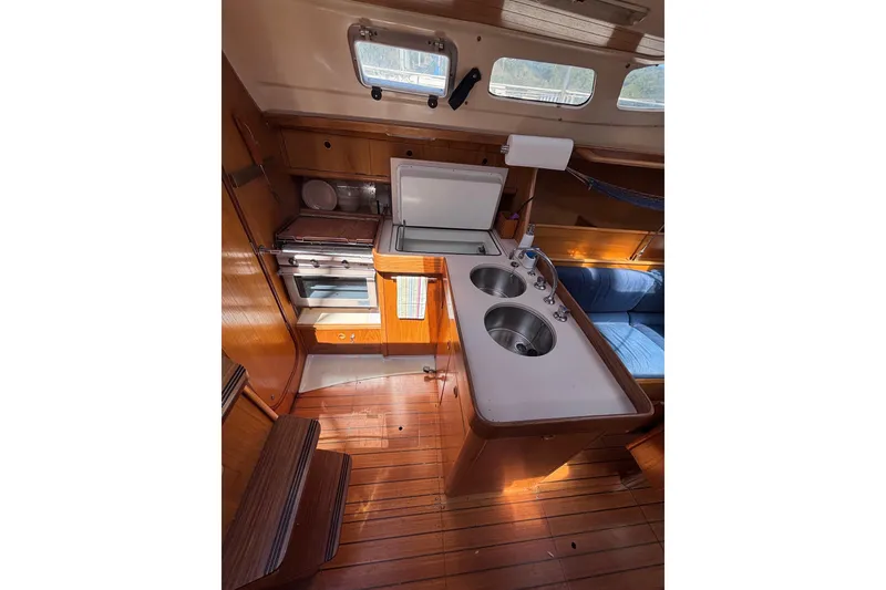 Slide: The Image of Interior of 1990 Beneteau Oceanis 350 yacht, featuring a compact kitchen with dual sinks. - 7