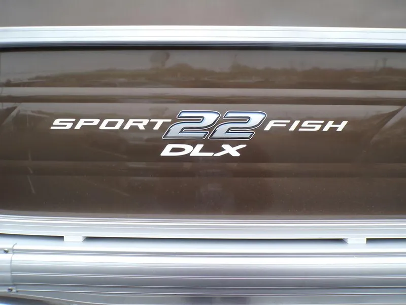 Slide: The Image of 2024 Sun Tracker SportFish™ 22 DLX logo on brown boat exterior. - 10