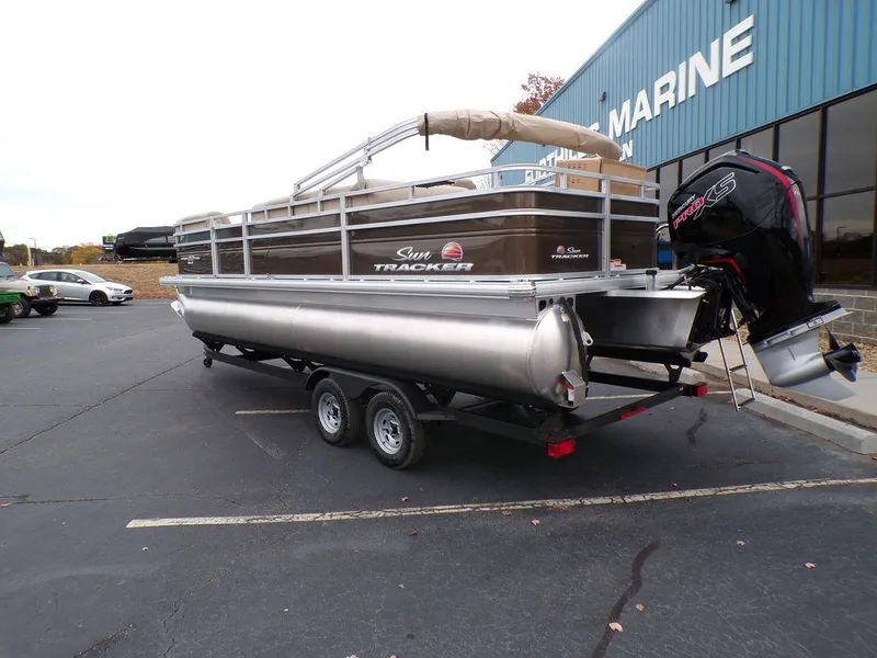 Slide: The Image of 2024 Sun Tracker SportFish™ 22 DLX pontoon boat on a trailer outside a marine dealership. - 4