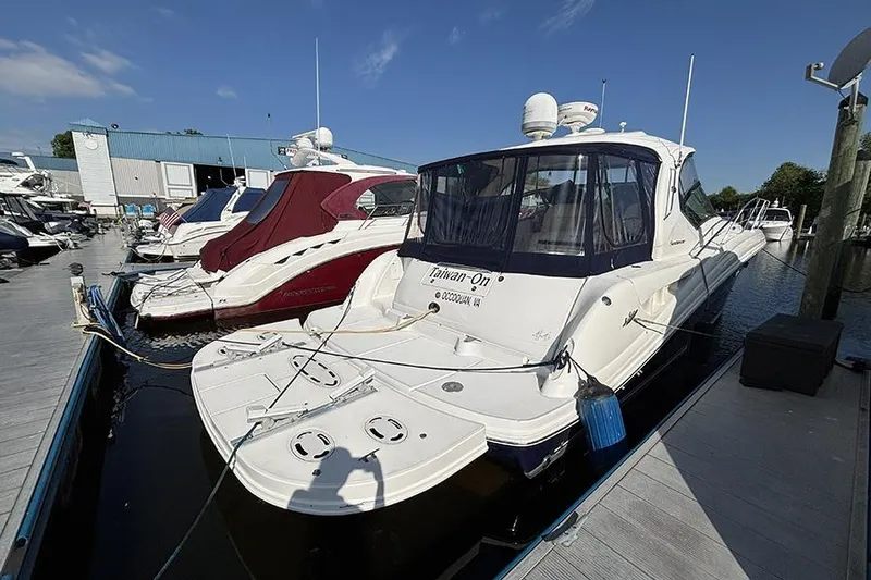 The Image of 2006 Sea Ray 44 Sundancer yacht docked at marina under clear blue sky. - 0