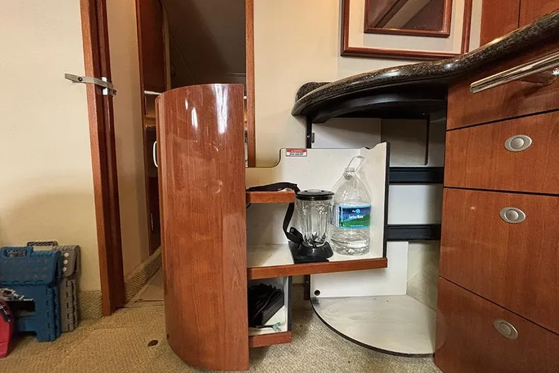 Slide: The Image of Interior of 2006 Sea Ray 44 Sundancer with open wooden cabinet and kitchen items. - 18