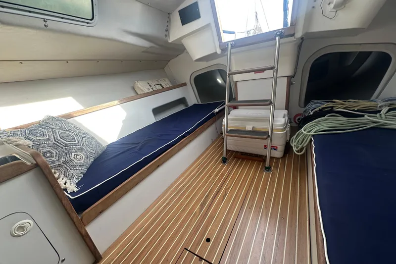Slide: The Image of Interior of a 1998 J Boats J/105 sailboat with wooden flooring and blue cushions. - 13