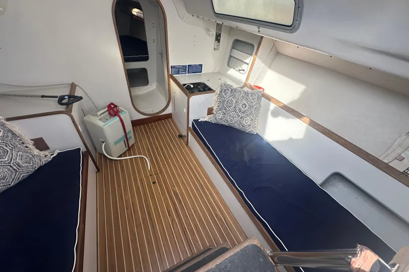 Slide: The Image of 1998 J Boats J/105 interior with wooden flooring, blue cushions, and patterned pillows. - 8