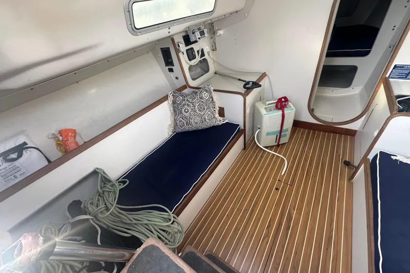 Slide: The Image of Interior of a 1998 J Boats J/105 sailboat with wooden flooring and blue cushions. - 9