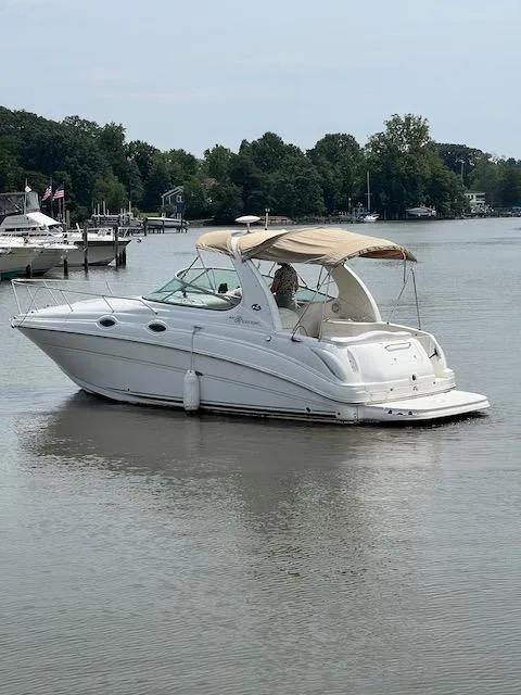 Slide: The Image of 2005 Sea Ray 280 Sundancer boat on calm water with trees in the background. - 1