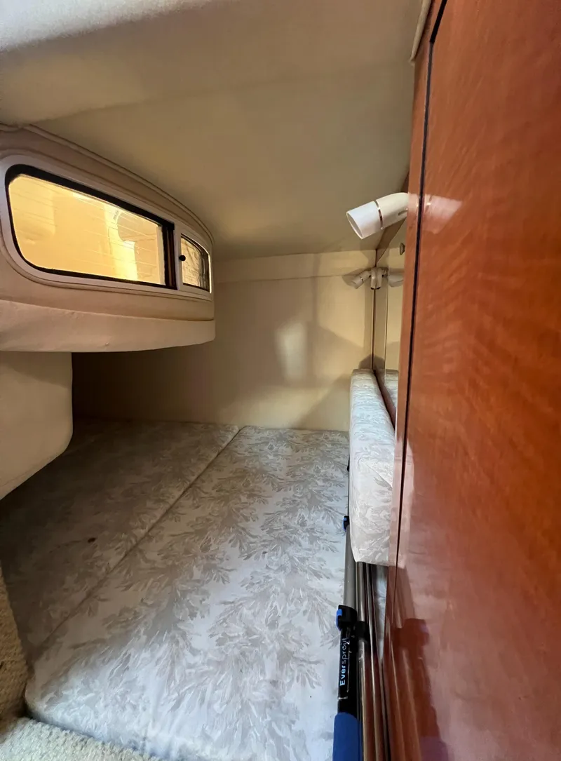 Slide: The Image of 2005 Sea Ray 280 Sundancer cabin interior with bed and wooden paneling. - 29
