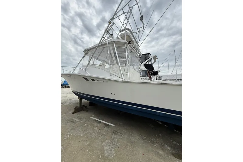 Slide: The Image of 1999 Luhrs Tournament 320 Open boat on dry dock, featuring a sleek white hull and tower. - 10