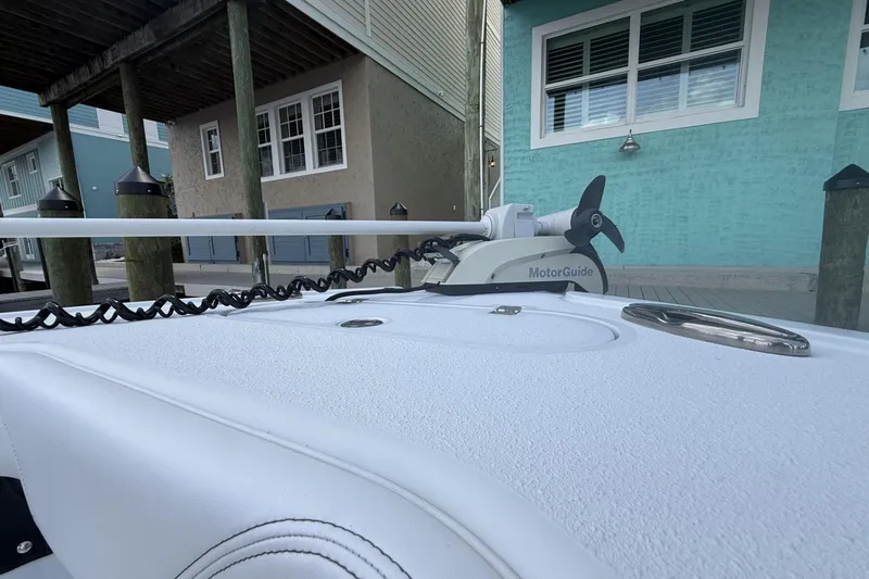 Slide: The Image of 2023 Yellowfin 26 Hybrid boat with MotorGuide trolling motor docked near waterfront homes. - 15