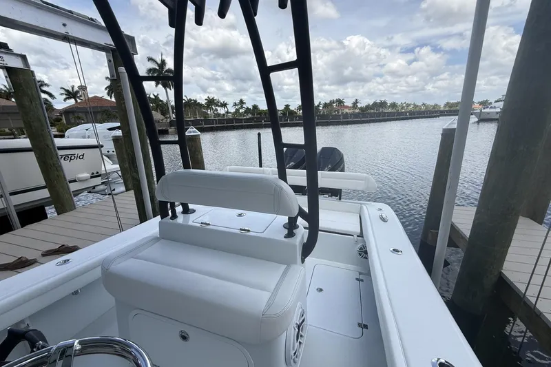 Slide: The Image of 2023 Yellowfin 26 Hybrid boat docked at marina, featuring sleek white seating and calm waters. - 18