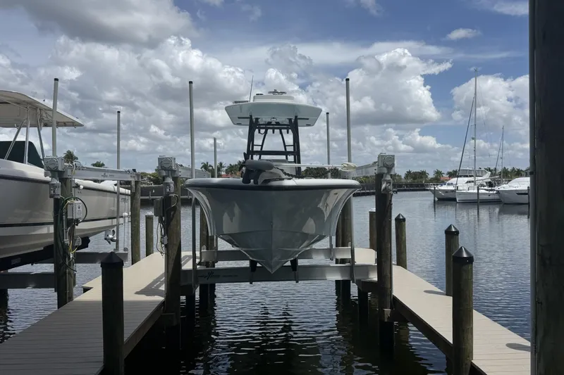 Slide: The Image of 2023 Yellowfin 26 Hybrid boat docked at marina under cloudy sky. - 2
