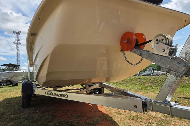 Slide: The Image of 2017 Carolina Skiff 198 DLX on EZ Loader trailer, parked on grass under a cloudy sky. - 2