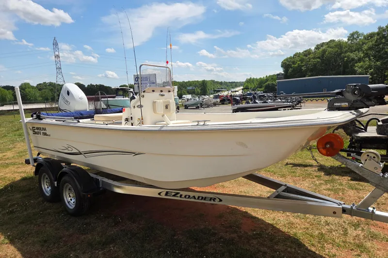 Slide: The Image of 2017 Carolina Skiff 198 DLX boat on trailer, parked outdoors under blue sky. - 3