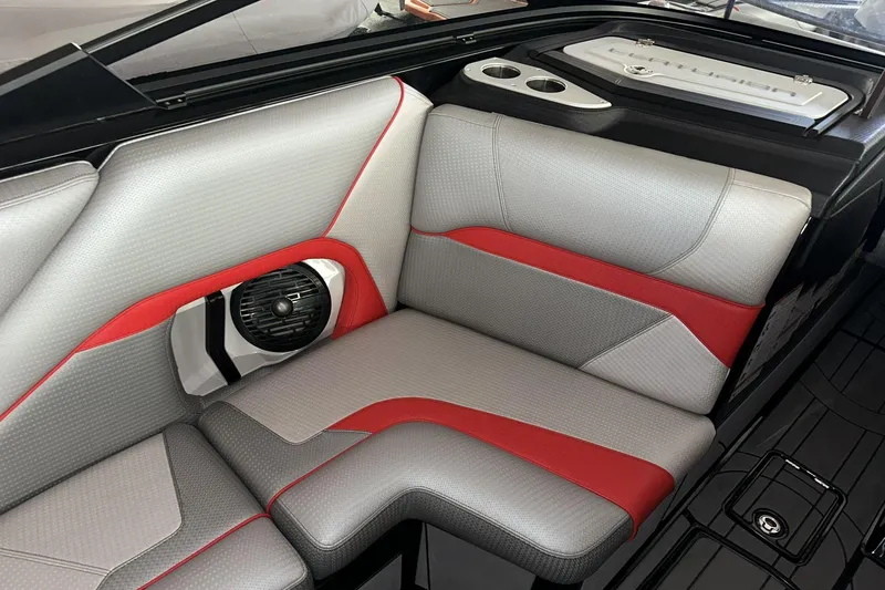 Slide: The Image of 2021 Centurion Ri245 boat interior with gray and red seating, speaker, and cup holders. - 10