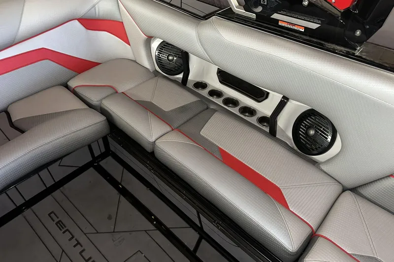 Slide: The Image of 2021 Centurion Ri245 boat interior with gray and red seating, speakers, and cup holders. - 11