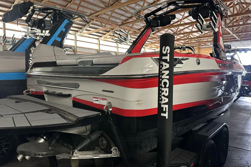 Slide: The Image of 2021 Centurion Ri245 boat in a showroom, featuring sleek red and white design. - 18