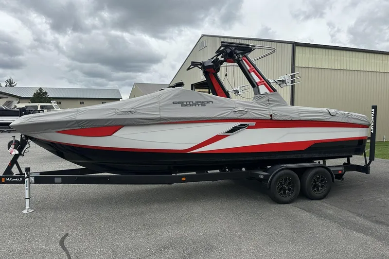 Slide: The Image of 2021 Centurion Ri245 boat covered on trailer, parked outdoors under cloudy sky. - 21