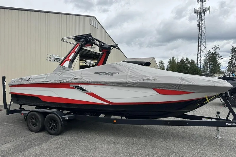 Slide: The Image of 2021 Centurion Ri245 boat on trailer, covered, with red and white accents, parked outdoors. - 22