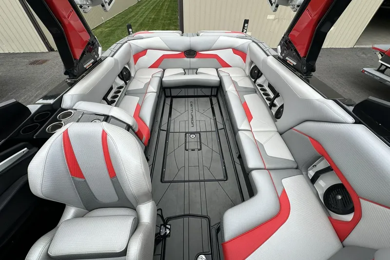 Slide: The Image of 2021 Centurion Ri245 boat interior with gray and red seating, cup holders, and speakers. - 23
