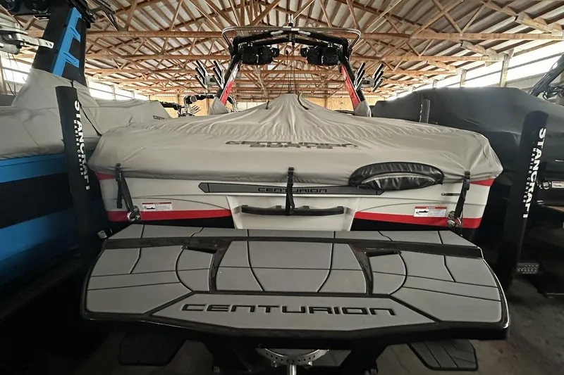 Slide: The Image of 2021 Centurion Ri245 boat with cover in storage, showcasing rear deck and branding. - 6