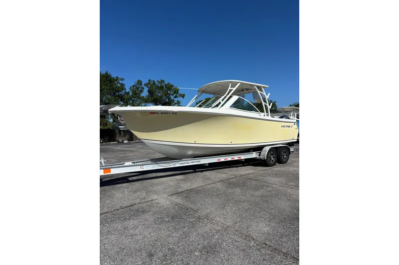 Slide: The Image of 2015 Sailfish 275 DC boat on trailer under clear blue sky. - 3