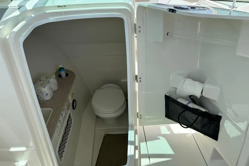 Slide: The Image of Interior of 2015 Sailfish 275 DC boat bathroom with toilet and storage. - 22