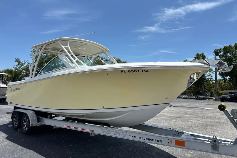 Slide: The Image of 2015 Sailfish 275 DC boat on trailer under clear blue sky. - 2
