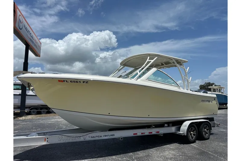 Slide: The Image of 2015 Sailfish 275 DC boat on trailer under a partly cloudy sky. - 1