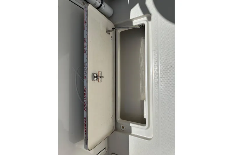 Slide: The Image of An open storage compartment on a boat with a white lid and latch. - 36