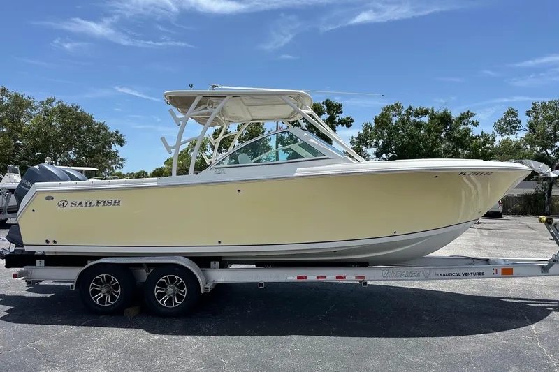 Slide: The Image of 2015 Sailfish 275 DC boat on trailer, parked outdoors under clear sky. - 3