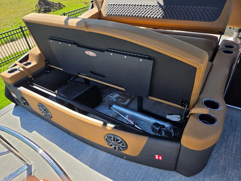 Slide: The Image of The image shows the storage area of a Harris Sunliner 230 pontoon boat with brown upholstery and speakers. - 26