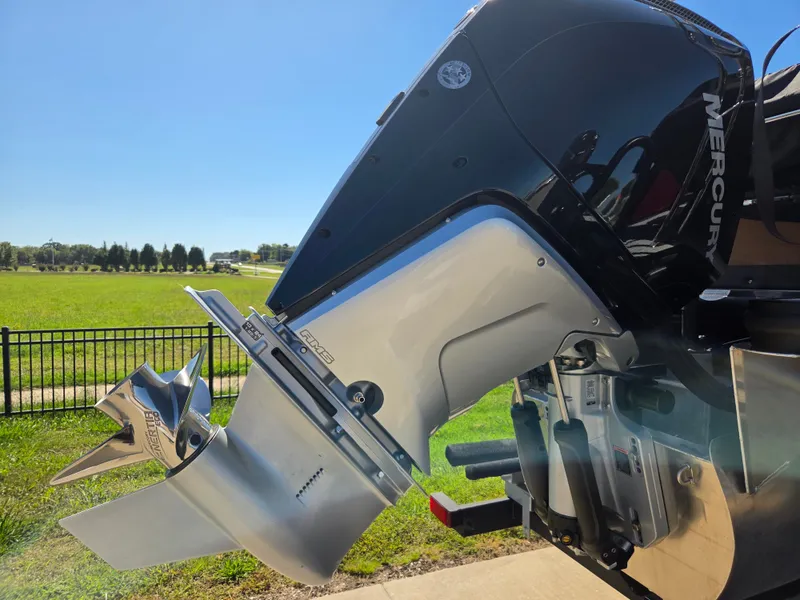 Slide: The Image of Close-up of a Mercury outboard motor on a boat, with a green field in the background. - 7