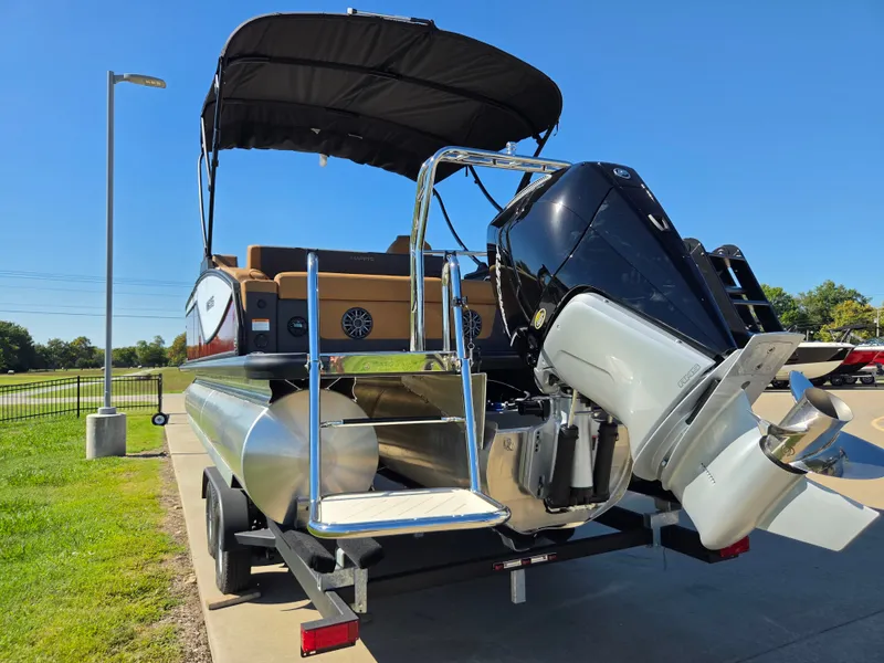 Slide: The Image of A 2027 Harris Sunliner 230 pontoon boat on a trailer. It features a large outboard motor and a black sunshade. - 5
