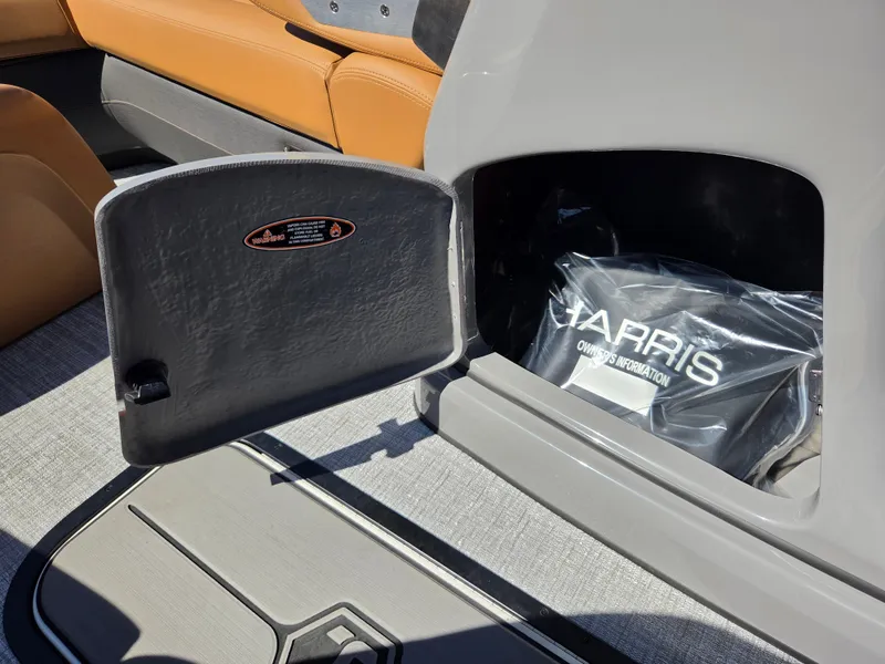 Slide: The Image of An open storage compartment on a Harris Sunliner 230 boat reveals a bag with the Harris logo. - 17
