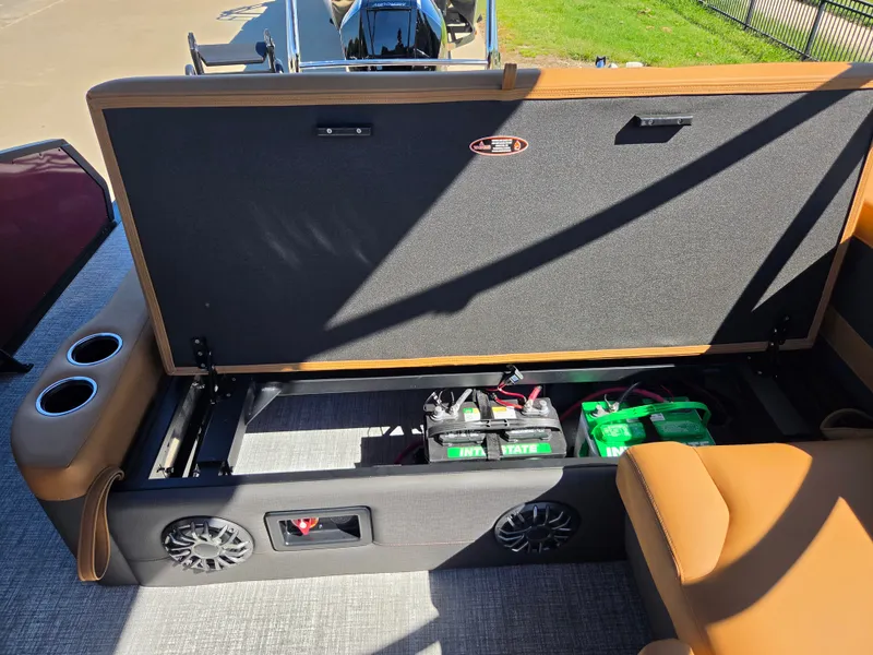 Slide: The Image of The image shows the storage area of a Harris Sunliner 230 boat with batteries and speakers. - 24