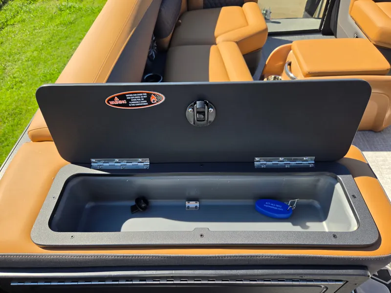 Slide: The Image of An open storage compartment on a Harris Sunliner 230 boat with brown upholstery. - 15