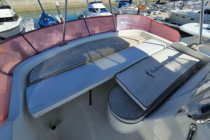 Slide: The Image of 1990 Mediterranean 38 Convertible yacht deck with cushioned seating in marina. - 12