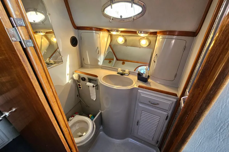 Slide: The Image of Bathroom interior of 1990 Mediterranean 38 Convertible yacht, featuring sink, toilet, and storage cabinets. - 34