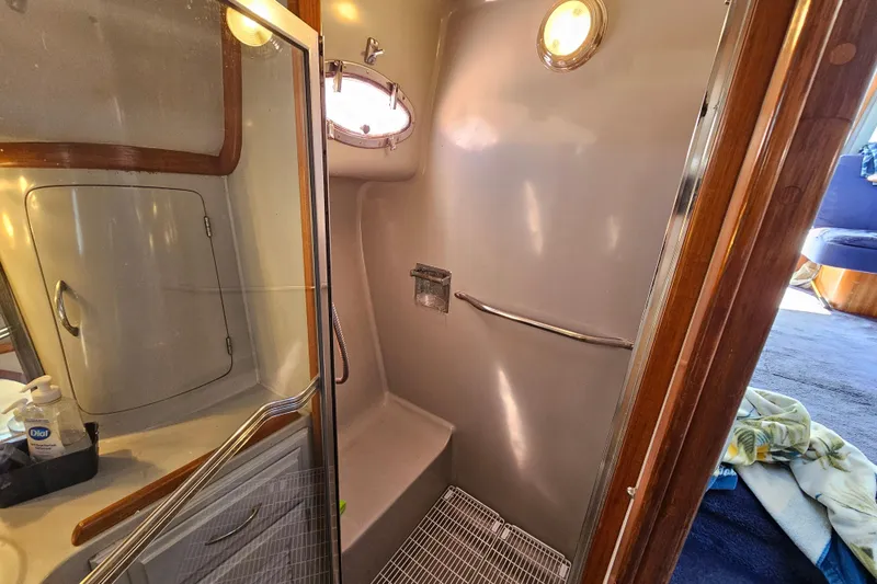 Slide: The Image of 1990 Mediterranean 38 Convertible yacht bathroom with shower, mirror, and porthole window. - 37