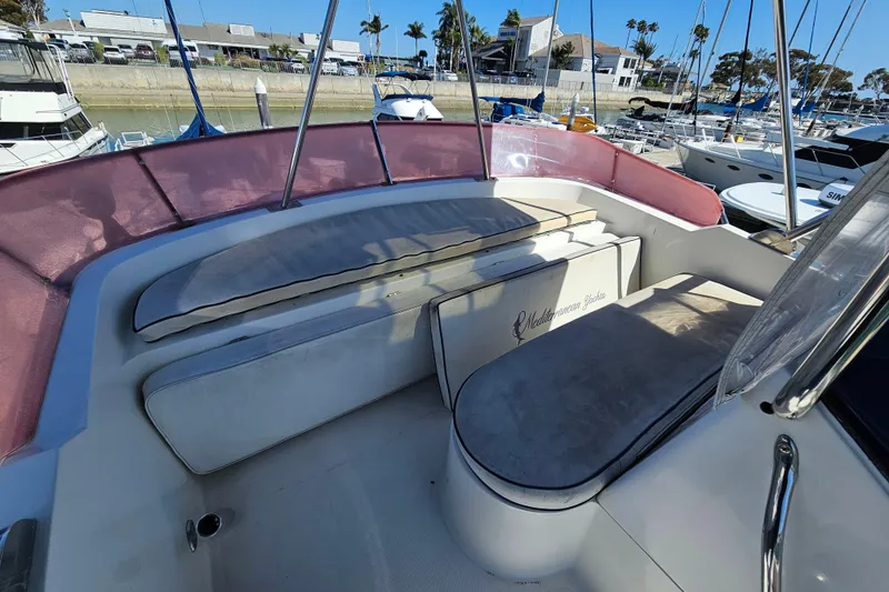 Slide: The Image of 1990 Mediterranean 38 Convertible yacht interior with cushioned seating and marina view. - 9