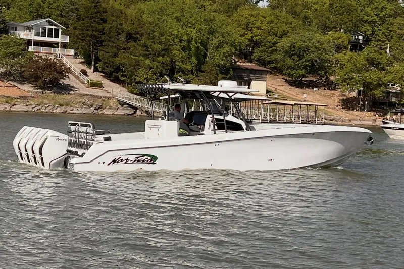 The Image of 2022 Nor-Tech 392 Super Fish boat cruising on a lake near a wooded shoreline. - 0