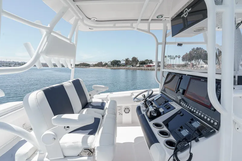 Slide: The Image of 2019 Fountain 38 CC boat cockpit with modern controls and seating, overlooking calm waters. - 49