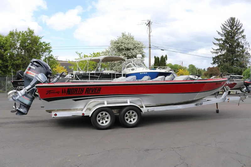 The Image of 2026 North River SCOUT boat on trailer, featuring red and silver design with Yamaha outboard motor. - 1