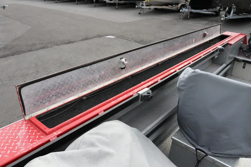Slide: The Image of 2026 North River SCOUT boat storage compartment with diamond plate cover, parked on asphalt. - 13