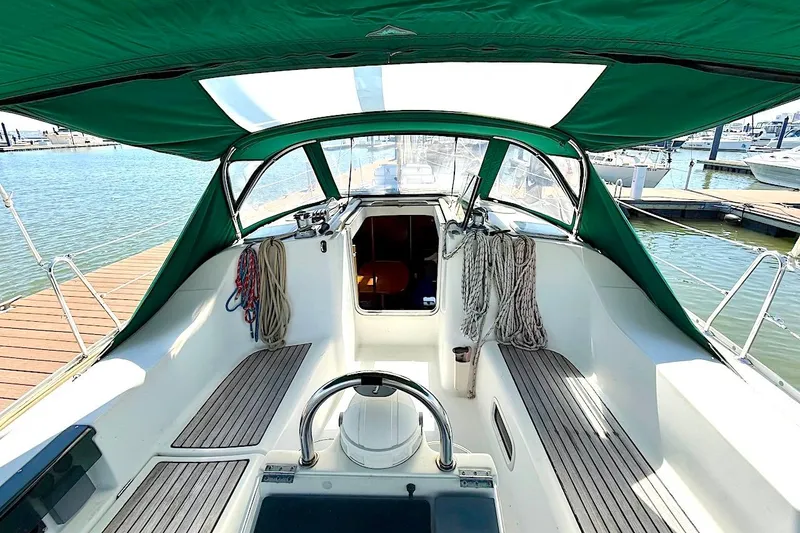 Slide: The Image of Cockpit of 2003 Beneteau 393 sailboat with green canopy and marina view. - 12