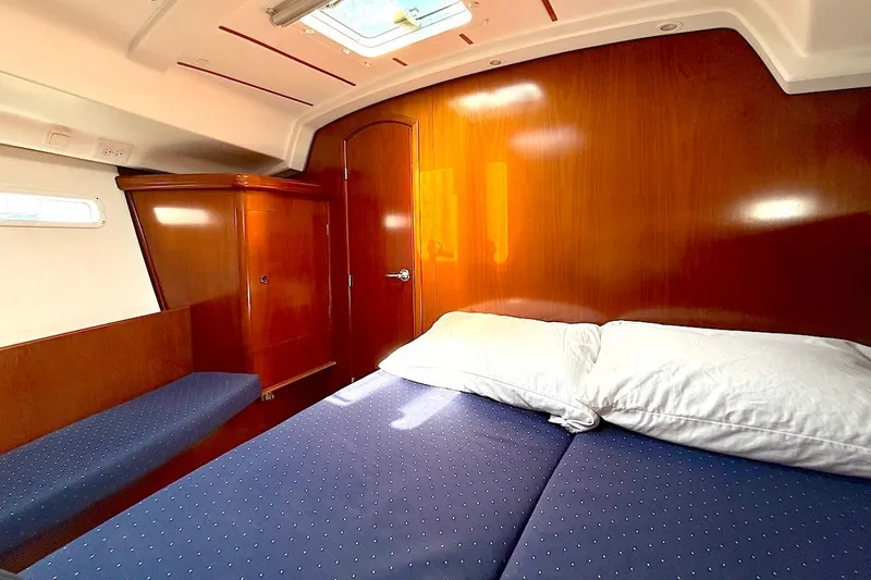 Slide: The Image of Cozy cabin interior of 2003 Beneteau 393 yacht with wooden finish and blue bedding. - 18