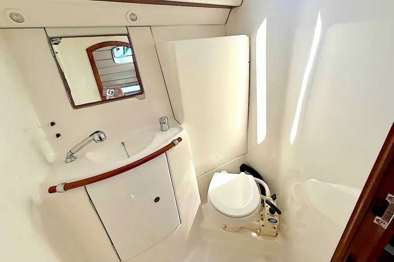 Slide: The Image of Compact bathroom in a 2003 Beneteau 393 yacht, featuring a sink, mirror, and toilet. - 20