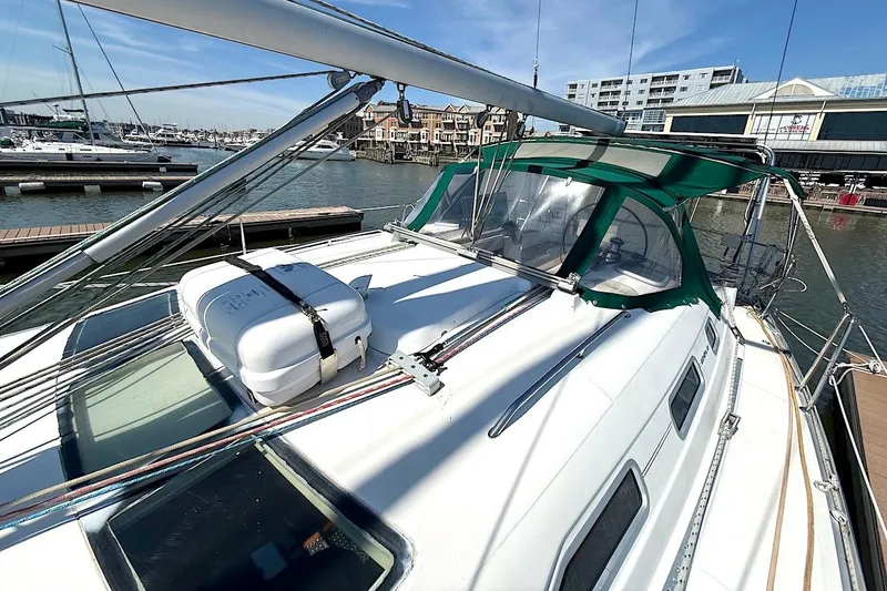 Slide: The Image of 2003 Beneteau 393 sailboat docked at marina, featuring green canopy and lifeboat. - 5