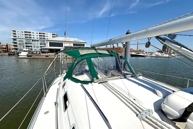 Slide: The Image of 2003 Beneteau 393 sailboat docked in marina, featuring green canopy and modern architecture backdrop. - 6