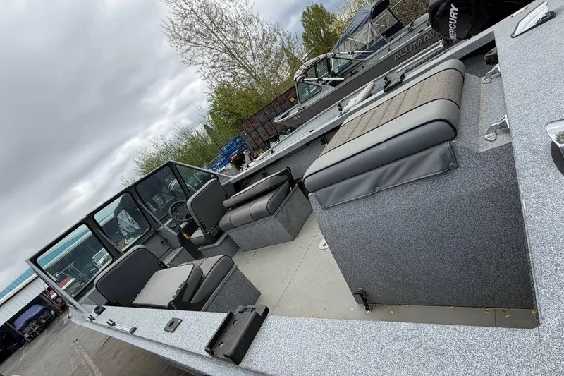 Slide: The Image of 2004 Alumaweld STRYKER 19 boat interior with seating and steering wheel, parked outdoors. - 6